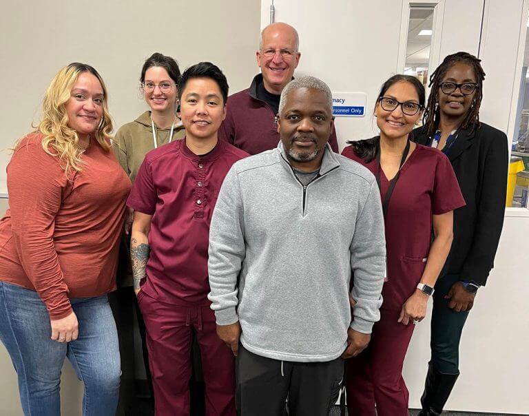 Seven PromptCare care team members standing in office.