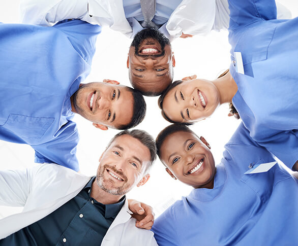 Group of smiling medical coworkers in a circle looking down at camera