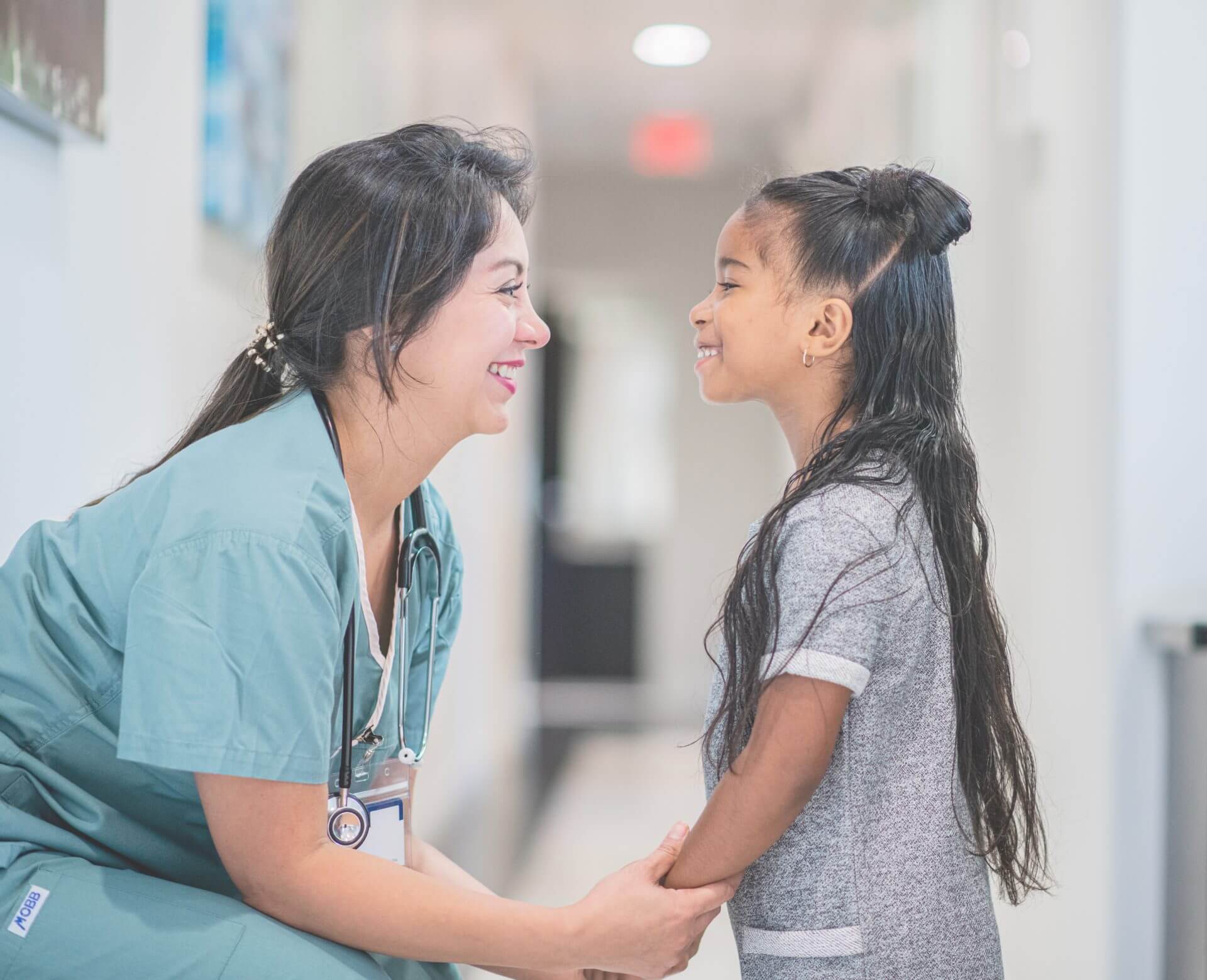 Nurse at eye level with adorable little girl smiling and looking each other in the eyes