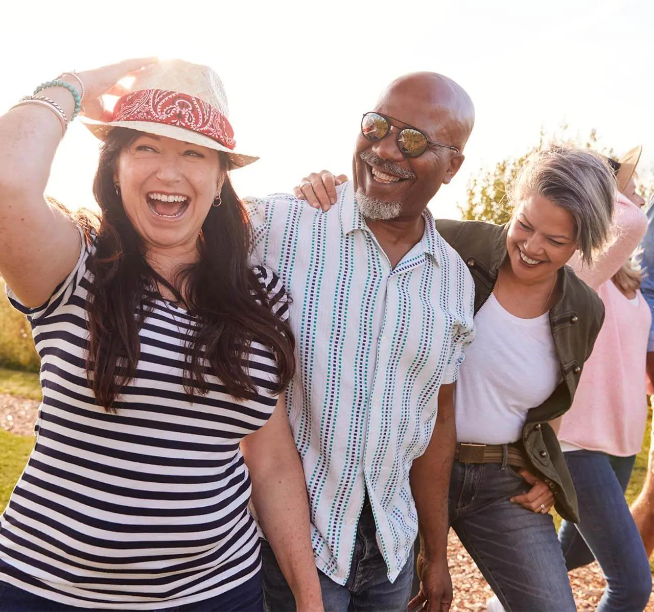 Group Of Mature Friends On Vacation Walking Along Path Through Campsite At Sunset