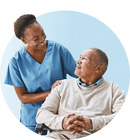 Nurse in blue scrubs walking her elderly patient in a wheelchair