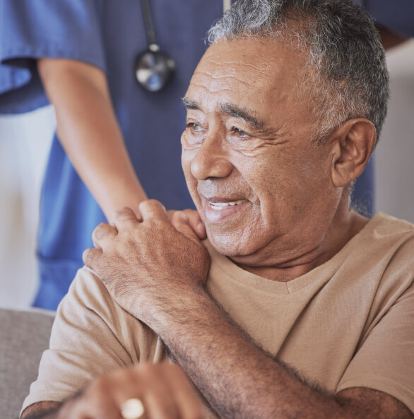 Older complex patient with nurse's hand on his shoulder giving him comfort.