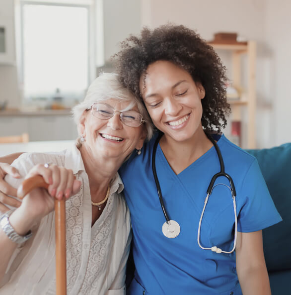 Caring nurse in blue scrubs hugging older female patient