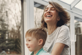 Toddler boy playing with happy mom outdoors