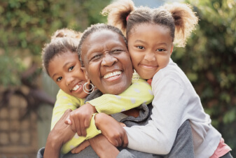 Happy grandmother being hugged by two granddaughters