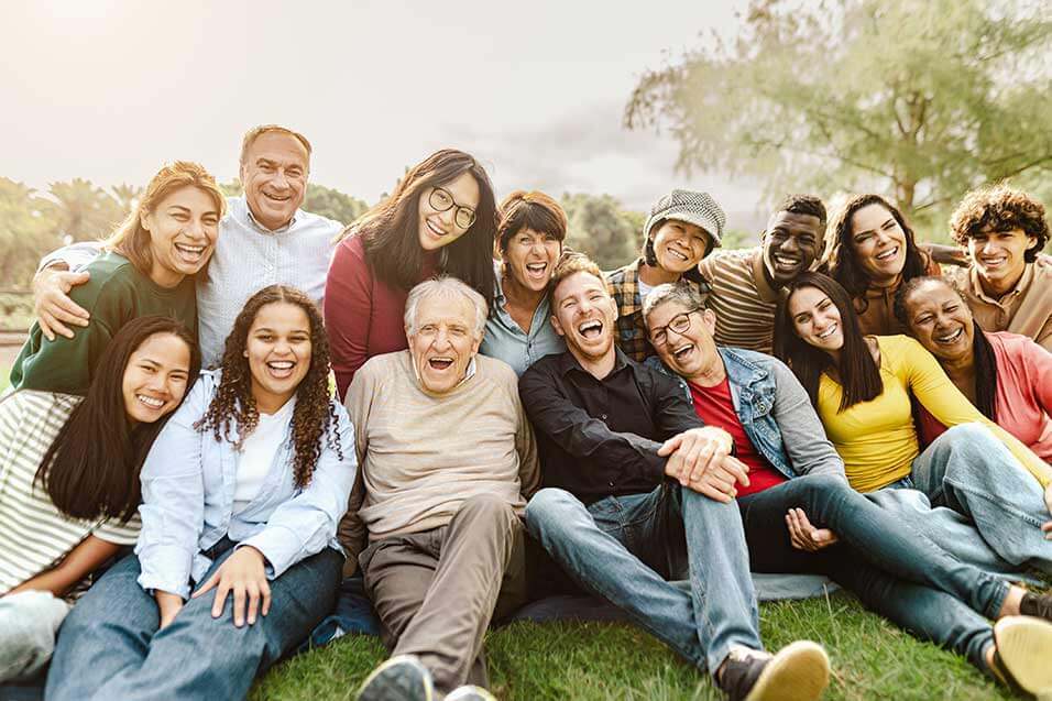 Large multigenerational and multiracial family sitting on grass smiling