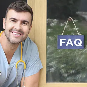 Nurse sitting next to door with FAQ sign
