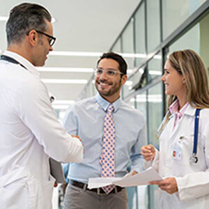 Businessman and two doctors talking in hospital shaking hands