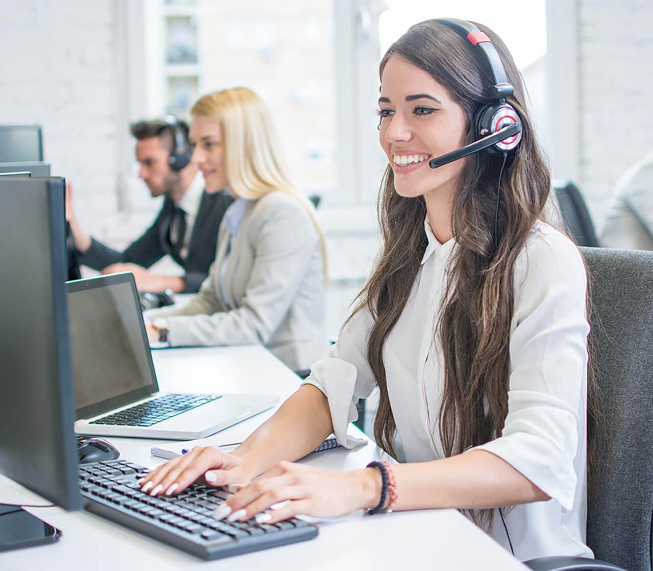 Woman sitting at computer with headset on answering support calls