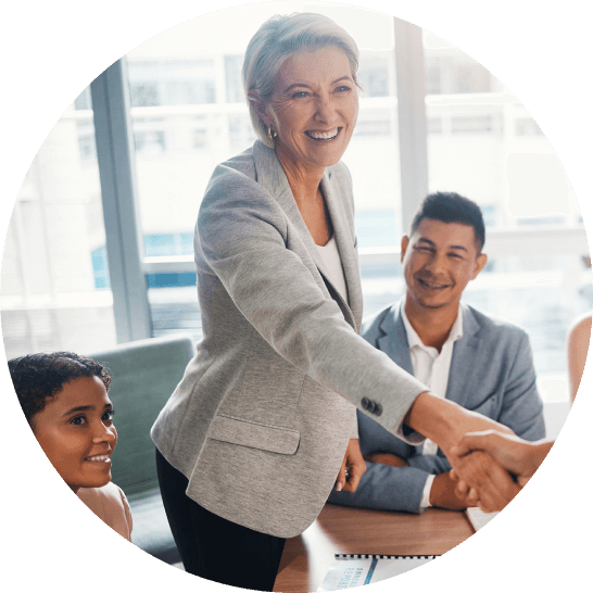 Business woman shaking hands with business partner at a meeting around a boardroom table