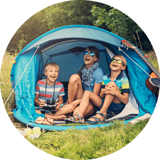 Three children sitting in a tent smiling and laughing