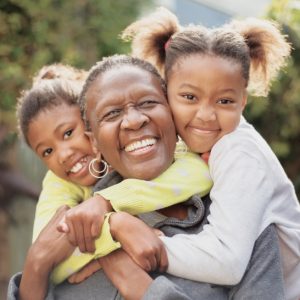 Grandmother being hugged to two young granddaughters