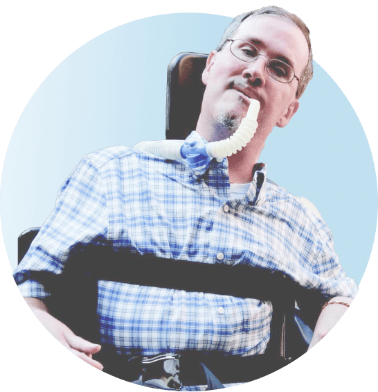 Male patient on a ventilator in a wheelchair smiling