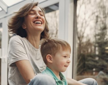 Mother and toddler son riding a toy outdoors.