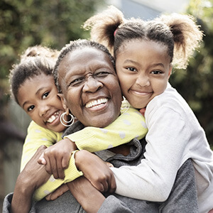 Smiling grandmother being hugged by two young granddaughters