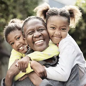 Smiling grandmother being hugged by two young granddaughters